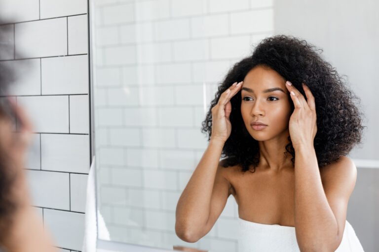 Girl looking frustrated in a mirror because of blackheads