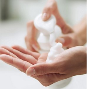 Woman pumping foaming facial wash into her hand