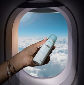 Woman holding a can of Deep Moisture Spray against a plane window