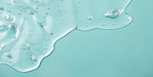 Close-up of a clear, gel-like essence on a blue background