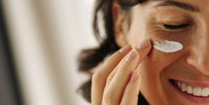 Woman with clear, radiant skin applying cream to her face