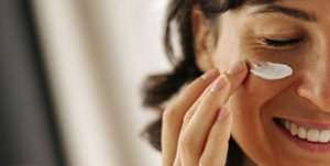 Woman with clear, radiant skin applying cream to her face