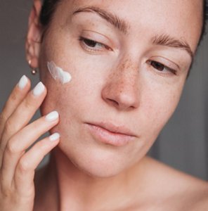 Woman with sensitive skin gently applying a moisturiser to her face