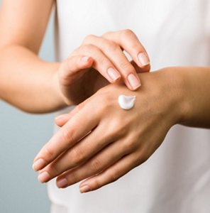 Woman with sensitive skin applying a moisturising cream to her hand