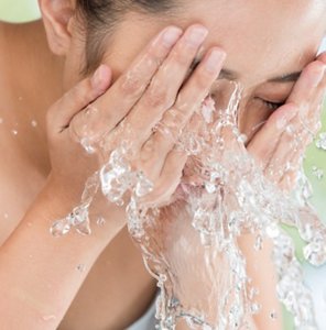 Woman washing her face with cool water