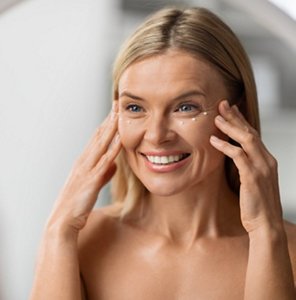 Happy older woman moisturising her face