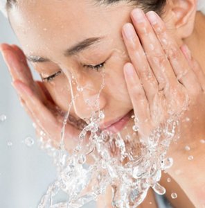 Woman rinsing her face after using a gentle foaming cleanser