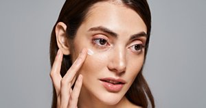 Woman with clear skin applying a moisturiser