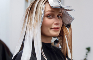 a first point of view from a barber who is power shine toning hair of a woman with goldwell Iridescent Blonde product