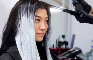 a first point of view from a barber who is alternate toning hair of a woman with goldwell Iridescent Blonde product