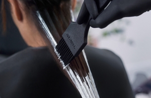 a first point of view from a barber who is full head toning hair of a woman with goldwell Iridescent Blonde product