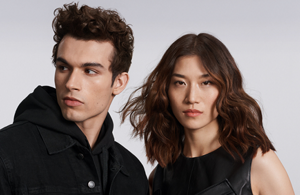 white woman with long blonde hair, which stands in front of a clean grey background looking into the camera