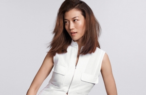 a white woman with brown long hair looking straight into the camera in front of a grey background
