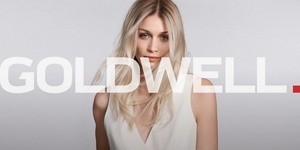 white woman with long blonde hair, which stands in front of a clean grey background looking into the camera