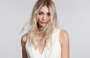 a black woman with short hair looking straight into the camera in front of a grey background