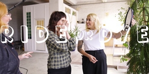 white woman with long blonde hair, which stands in front of a clean grey background looking into the camera