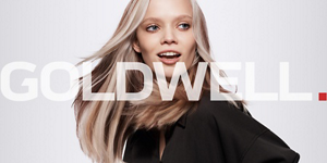 Blonde woman with straight hair in front of a bright background  and Goldwell logo in front.