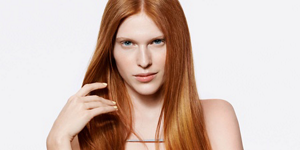 Serious looking woman with red straight hair and bright background