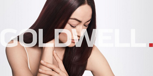 Woman with brown straight hair looking down over grey background and Goldwell logo in front