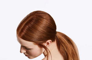 vrouw met rood, lang haar met een lage paardenstaart voor een heldere/grijze achtergrond