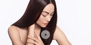 Woman with brown straight hair and light/grey background with play sign