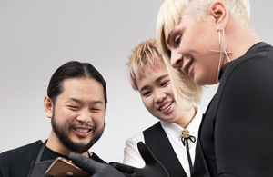 Tre parrucchieri sorridenti che guardano un device