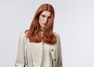 Two women with brown and red hair, using products from the Goldwell Muted Collection, standing in front of a grey background.