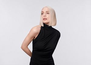 Two women with brown and red hair, using products from the Goldwell Muted Collection, standing in front of a grey background.