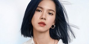 Woman with grey hair smiling and glancing at her right on light grey background