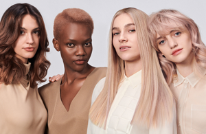 four diverse woman with different hair colors and lenghts, which stand side by side and close to each other looking into the camera while standing in front of a clean grey background
