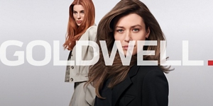 Zwei Frauen mit braunem und rotem Haar, die Produkte aus der Goldwell Muted Kollektion verwenden, stehend vor einem grauen Hintergrund.