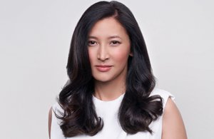 a woman with black wavy hair used goldwell structure and shine products on a grey background looking into the camera