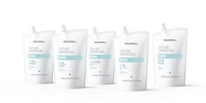 a woman with brown curly hair used goldwell texture dimensions perm product line on a grey background looking into the camera