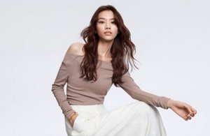 a woman with brown straight hair used goldwell structure and shine products on a grey background looking into the camera