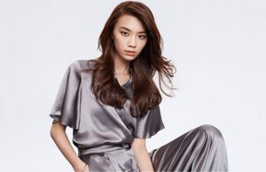 a woman with black wavy hair used goldwell structure and shine products on a grey background looking into the camera