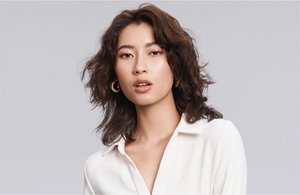 a man with brown curly hair used goldwell texture dimensions perm product line on a grey background