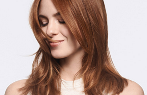 woman with red long straight hair looking down to the left over grey background