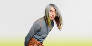 white woman with long blonde hair, which stands in front of a clean grey background looking into the camera