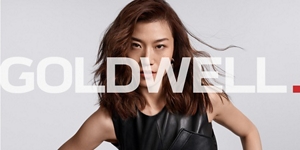 white woman with long blonde hair, which stands in front of a clean grey background looking into the camera