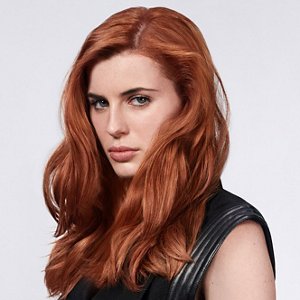 a red hair woman with beautiful long hair who used goldwell hair products on a grey background