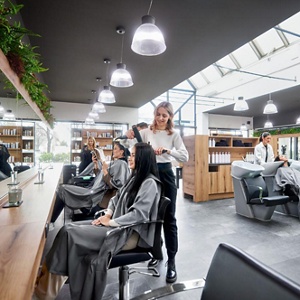 Hair stylists work on their clients hair in an open-plan, well-lit salon