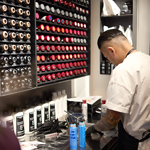  Goldwell Global Color Master, Peter Wu, expertly prepares hair color and foils for his clients in his salon, with an extensive range of Goldwell products in racks on the wall in front of him. 