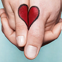 Goldwell's full stop logo: Two hands holding each other where the thumbs are facing the camera. On the thumbs is a red heart with a black outline that spans the gap between the two