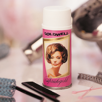 An early Goldwell Sprughold canister sits amongst other hair care products such as handheld mirrors, claw clips and parting combs