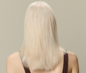 A before and after comparison of a woman's hair, showing the transformation from brown hair to beautiful shiny platinum blonde hair thanks to using Goldwell's Light Dimensions products.