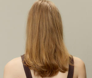 A before and after comparison of a woman's hair, showing the transformation from brown hair to beautiful shiny platinum blonde hair thanks to using Goldwell's Light Dimensions products.