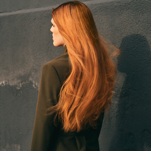  A model's long, orange hair floats in the wind thanks to the nourishing, hydrating and bodifying Goldwell range
