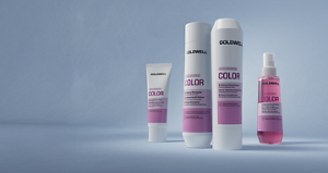 Goldwell Dualsenses Color haircare range displayed as white and pink shampoo, conditioner, treatment and spray products on a soft blue studio background.