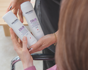 Salome De Wet shows her hair styling client the Dualsenses Color Brilliance Shampoo and Conditioner as part of the appointment
