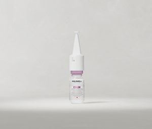 Goldwell Dualsenses Color Intensive Restoring Serum small white bottle standing upright on a soft light grey studio background.